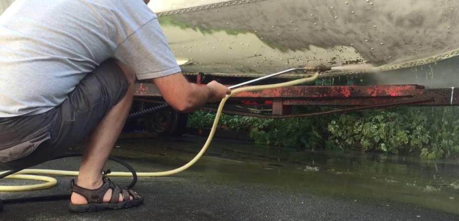 A man water blasting the underneath of a boat